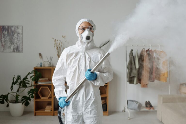 Technician in full protective gear treating a room